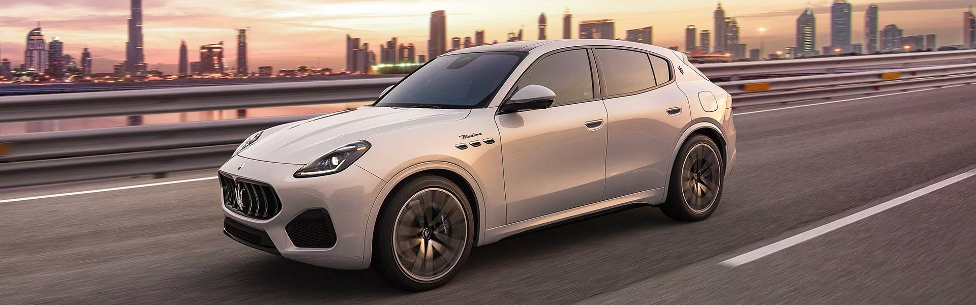 Silve color Maserati grecale riding in a city during sunset.